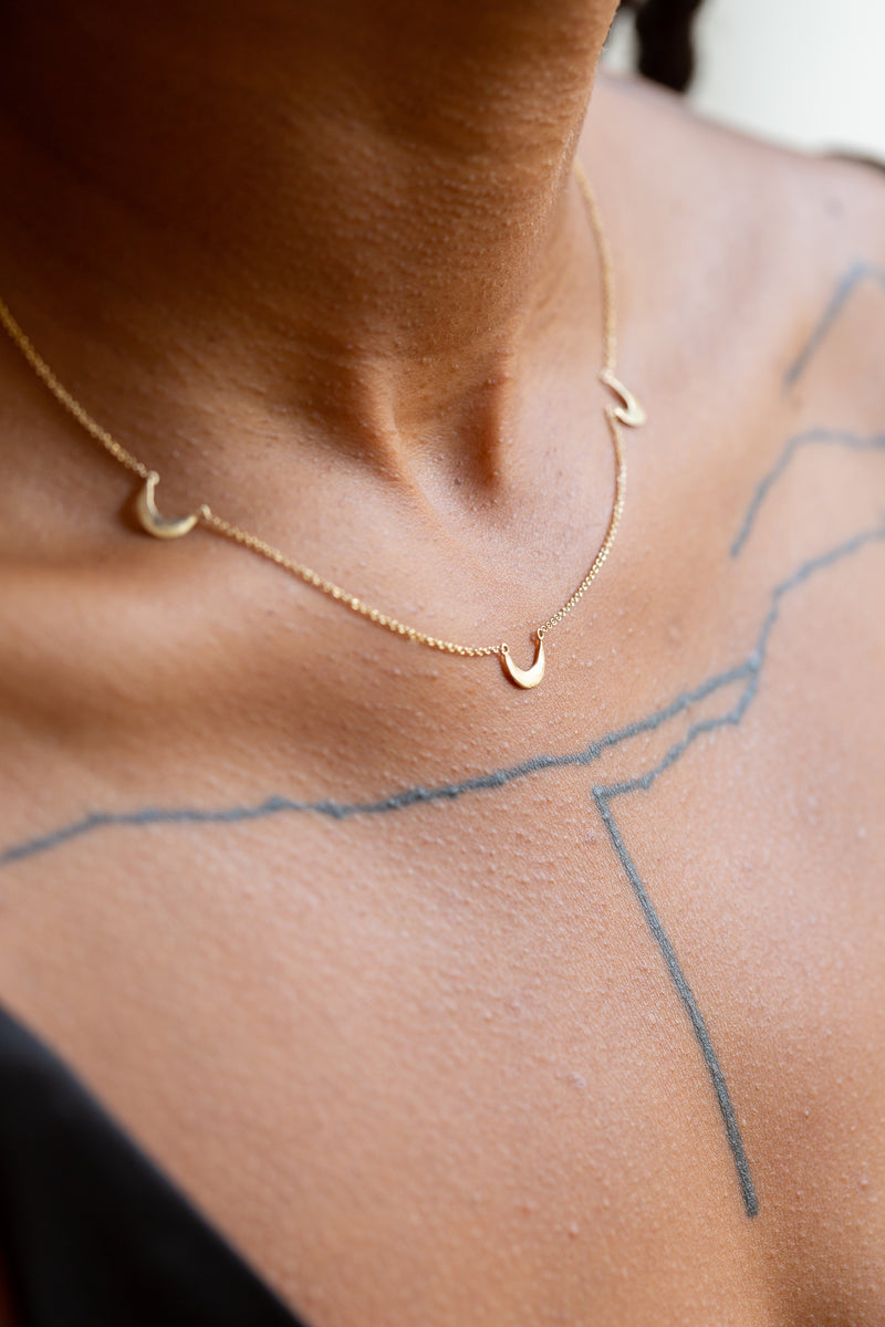 Person wearing Moon+Arrow's fine jewelry triple crescent moon necklace