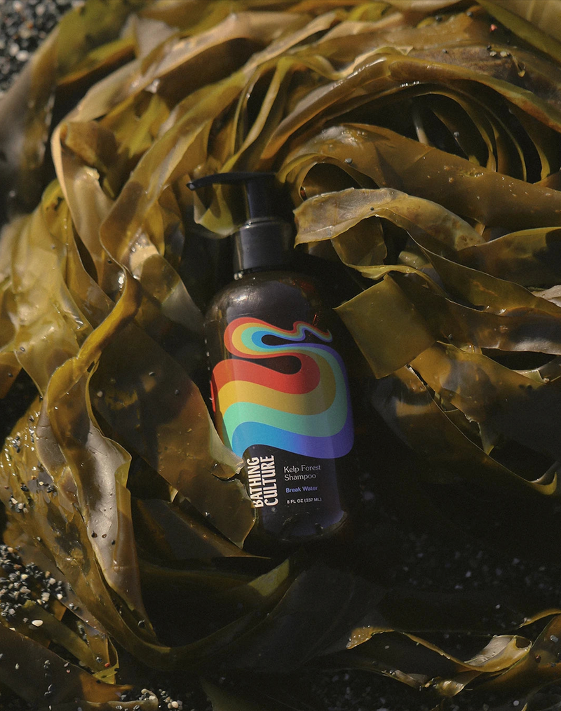 A bottle of Bathing Culture Kelp Forest Shampoo laying in a pile of kelp