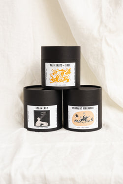A stack of three scents from 6pm candle in their boxes. The image includes scents Palo Santo, Speakeasy, and Midnight Marauder.