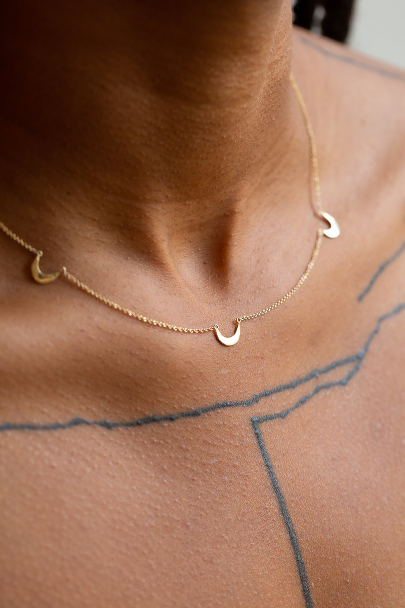 Person wearing Moon+Arrow's fine jewelry triple crescent moon necklace