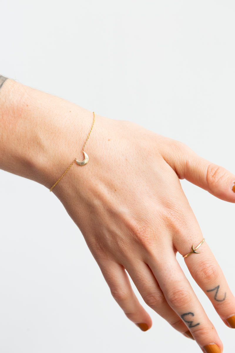 Person wearing Moon+Arrow's fine jewelry crescent moon bracelet in 10kt yellow gold