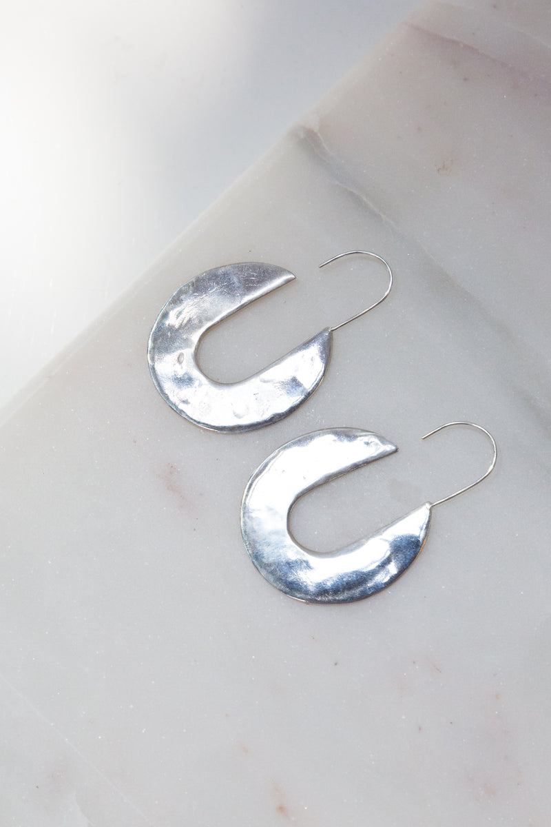A pair of Moon+Arrow's fortune earrings in sterling silver