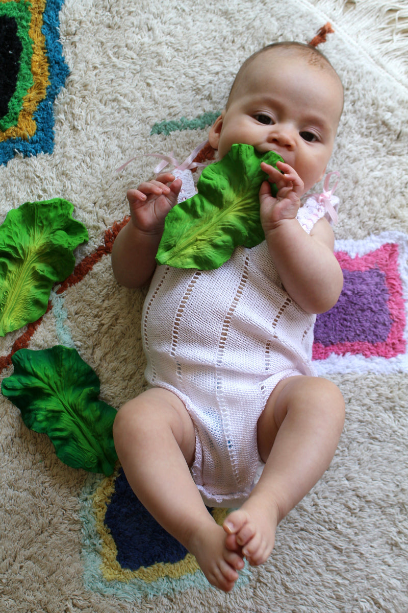 A baby holding Oli & Carol Kendall the Kale, all natural rubber toy