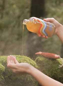 A person pouring out a bottle of Bathing Culture Mind and Body Wash, organic, biodegradable, all-purpose soap