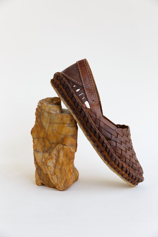 Mohinders Woven Flat Shoes in Walnut leaning against a rock