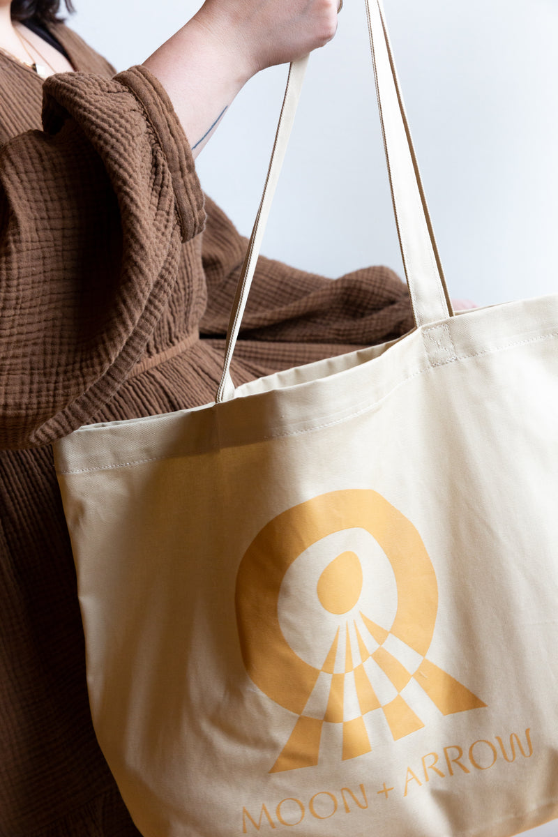 A person holding Moon+Arrow's tote bag made with 100% organic cotton
