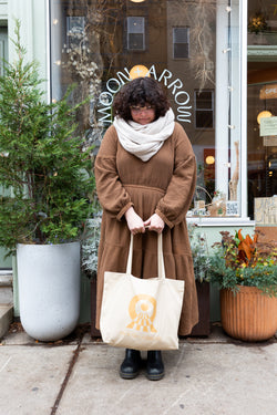 A person holding Moon+Arrow's tote bag made with 100% organic cotton