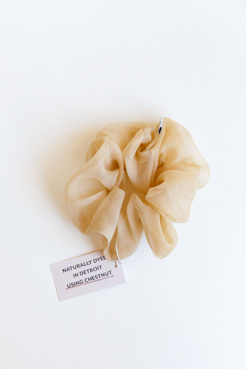 One beige colored Rosemarine scrunchies made with silk organza and dyed using plant matter and organic materials in Detroit