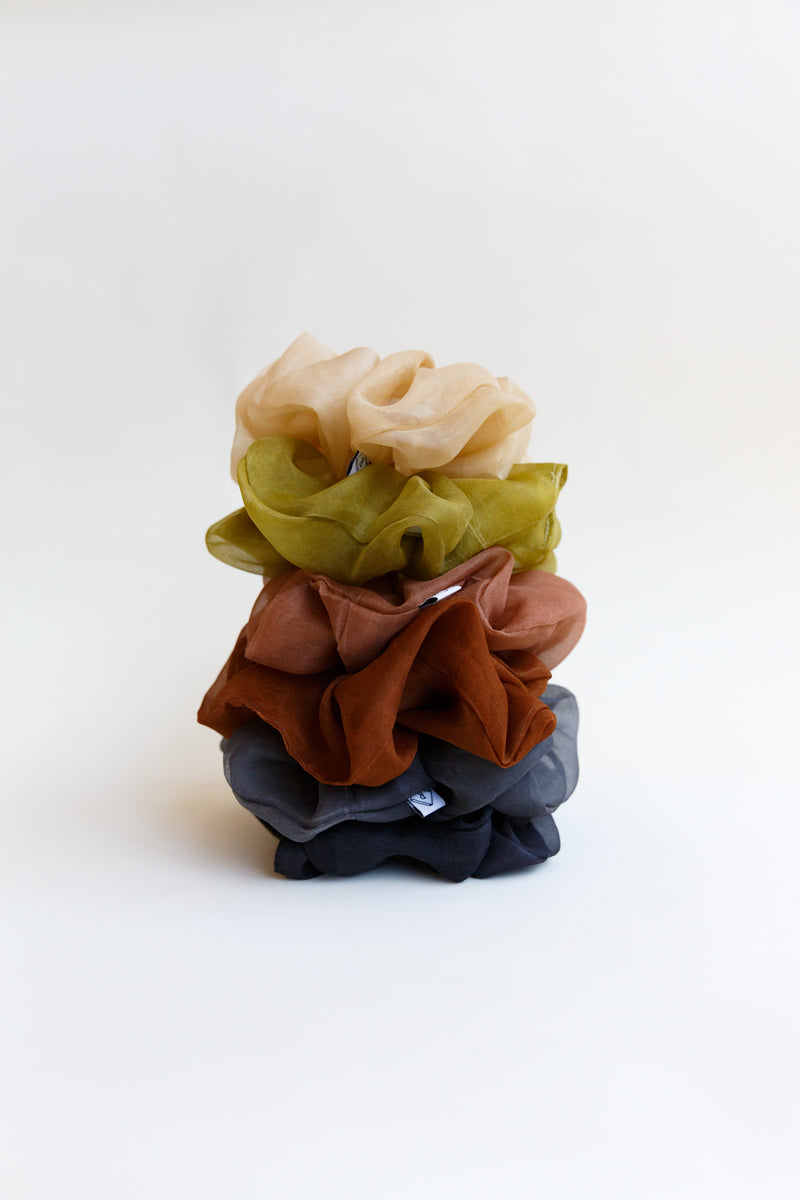 A stack of different colored Rosemarine scrunchies made with silk organza and dyed using plant matter and organic materials in Detroit