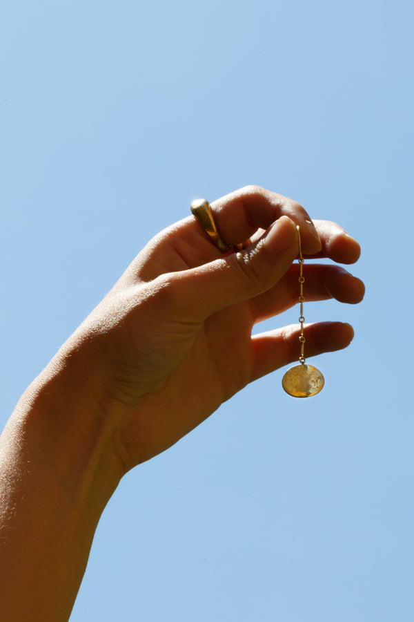 Person holding up Moon+Arrow's swaying full moons earrings