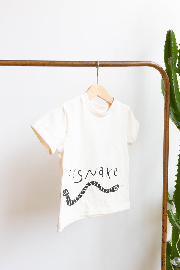 A baby Joan Ramone snake t-shirt made of 100% organic cotton with a slithering snake hand-printed on front and back, hung on a hanger