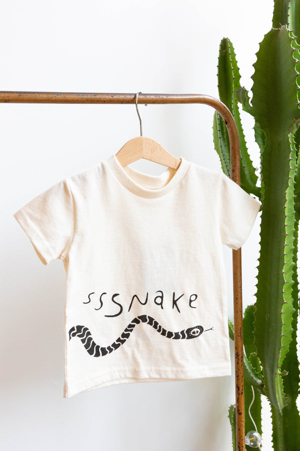 A baby Joan Ramone snake t-shirt made of 100% organic cotton with a slithering snake hand-printed on front and back, hung on a hanger