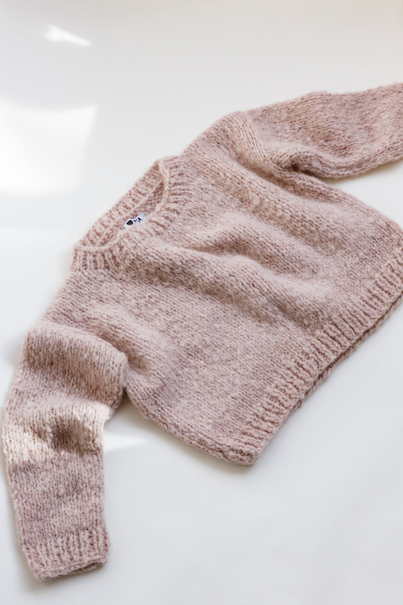 Handcrafted by women artisans in Argentina, this mohair pullover crop sweater is on display on a flat table