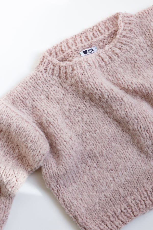 Handcrafted by women artisans in Argentina, this mohair pullover crop sweater is on display on a flat table