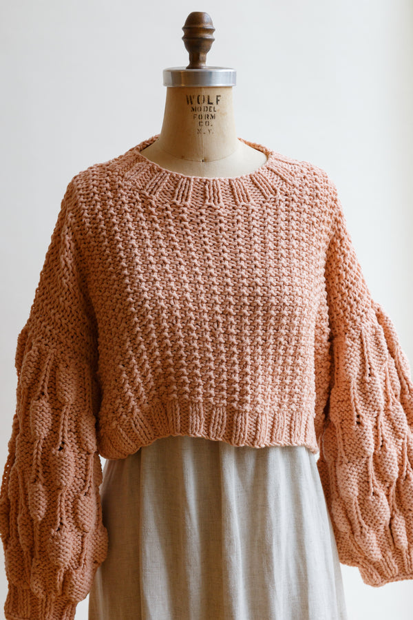 Handcrafted by women artisans in Argentina, this oversized chunky cotton pullover sweater features balloon sleeves from Ursa Textiles and is on display on a mannequin