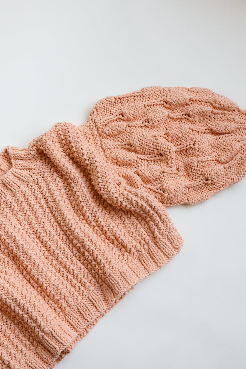 Handcrafted by women artisans in Argentina, this oversized chunky cotton pullover sweater features balloon sleeves from Ursa Textiles and is on display on a flat table