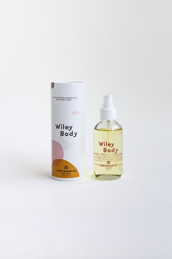 A bottle of Wiley Body Everywhere Oil, crafted from a skin-loving botanical blend of lightweight cold-pressed oils, sitting on a table