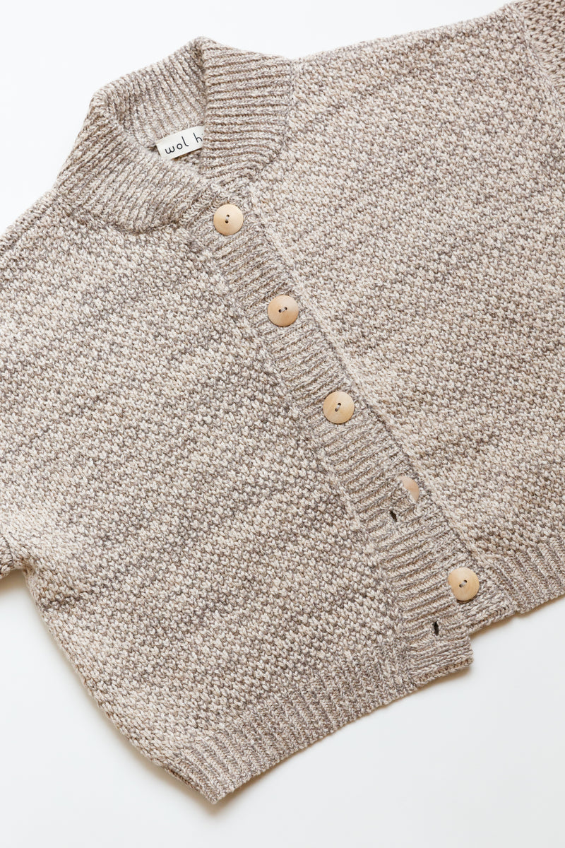 A cropped wide cardigan featuring unvarnished wood buttons and a high, rounded collar made of wool/alpaca blend chain yarn is on display on a flat table